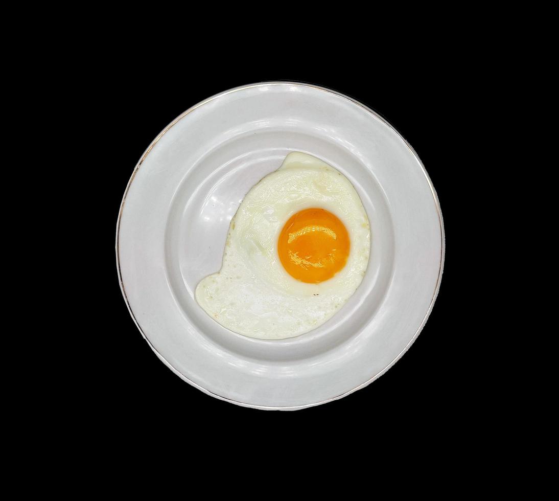 sunny side up egg served in white plate isolated in black background photo