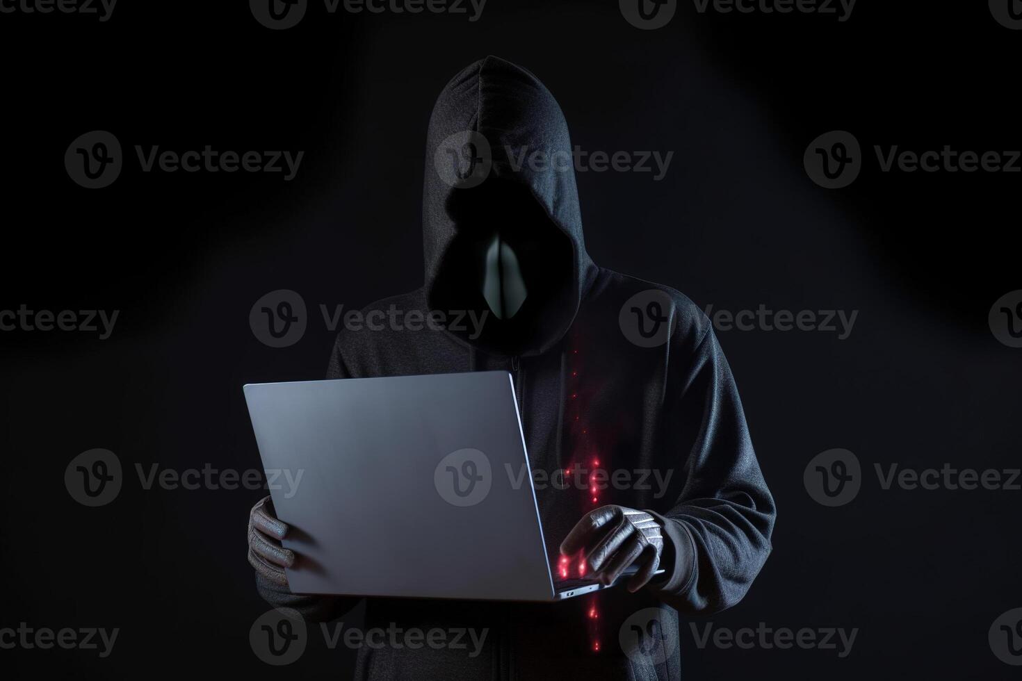 a hacker in a hoodie using a laptop computer isolated on dark background with neon light. photo