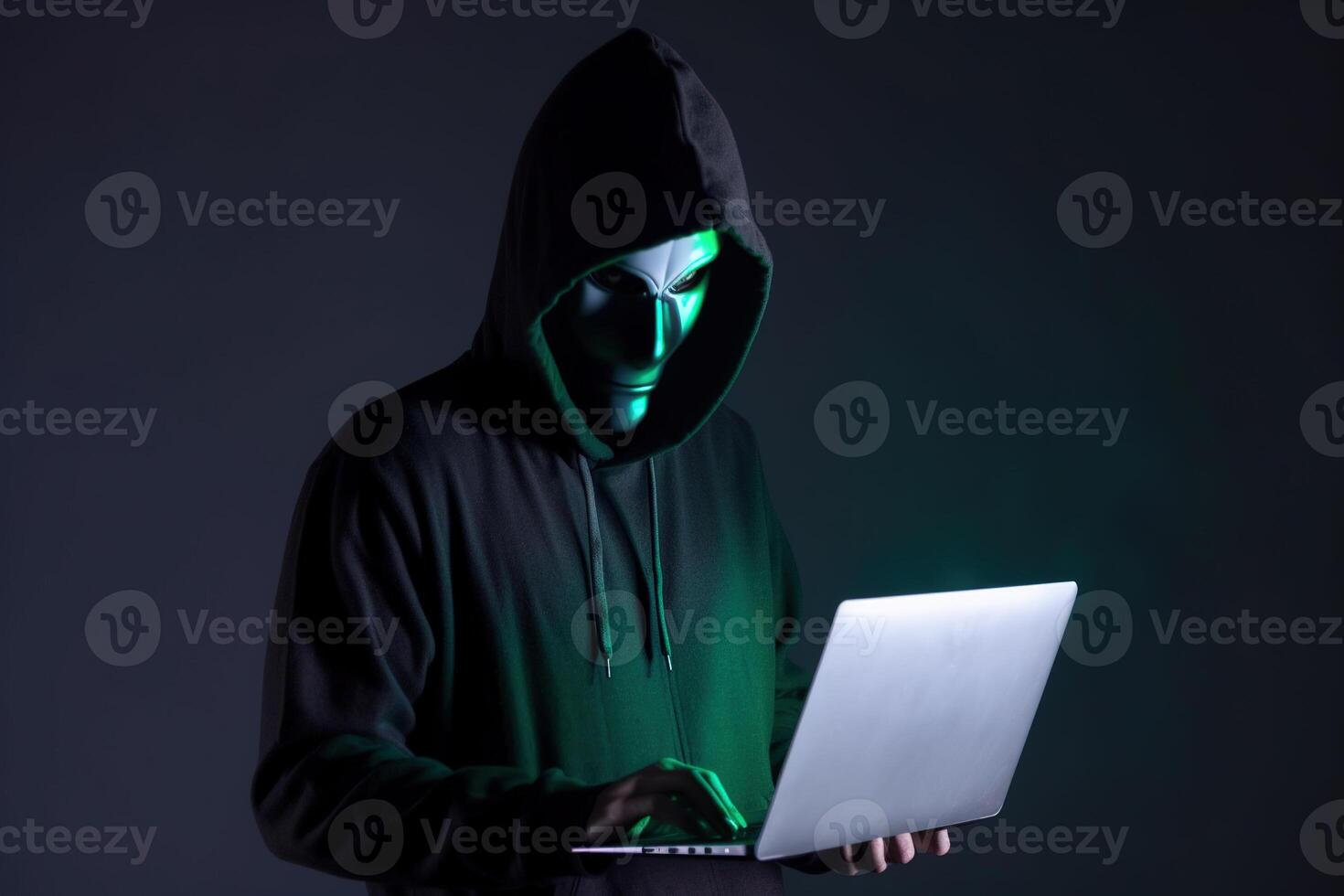 a hacker in a hoodie using a laptop computer isolated on dark background with neon light. photo