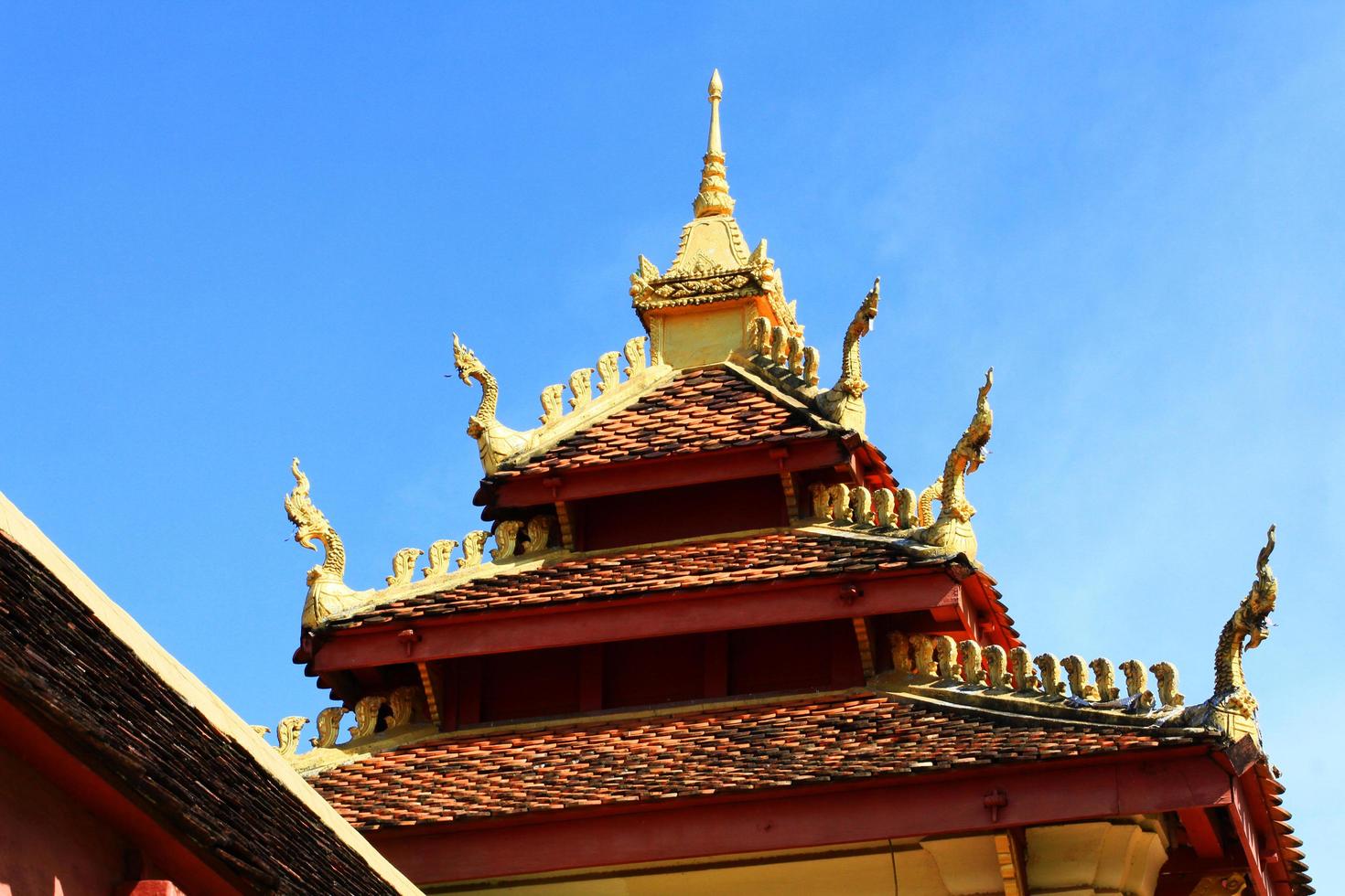 Golden naga on Art Roof of Buddhist temple with blue sky in Wat Pha That Luang Temple Vientiane Province, LAOS photo