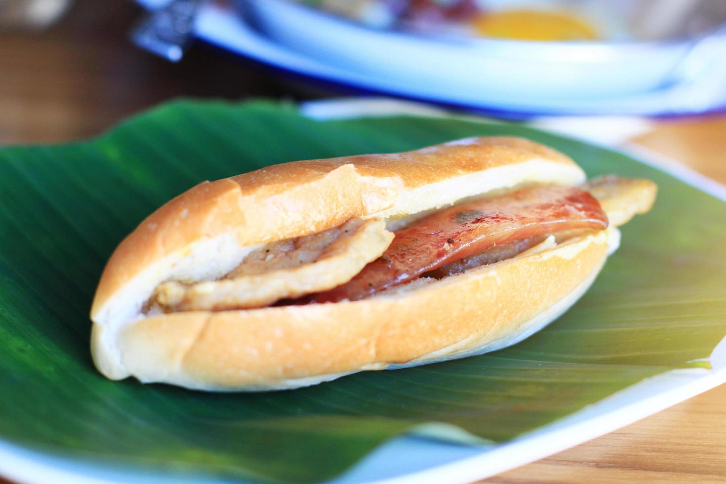 Baguette bread sandwich with cheese, ham on fresh Green banana leaf on wooden table in homemade Thai style photo