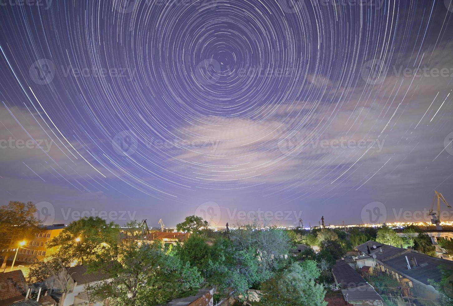 tracks of stars in night sky above city photo