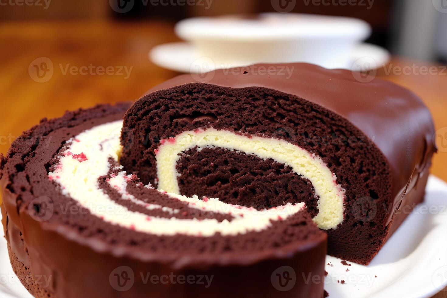 A swiss roll on a white plate on a wooden table. Homemade chocolate roll. Red velvet cake. photo