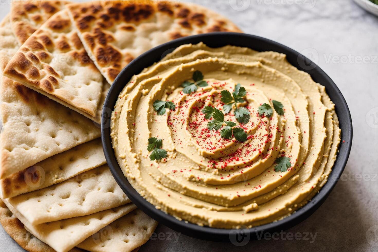 A bowl of hummus sits on a wooden table. photo