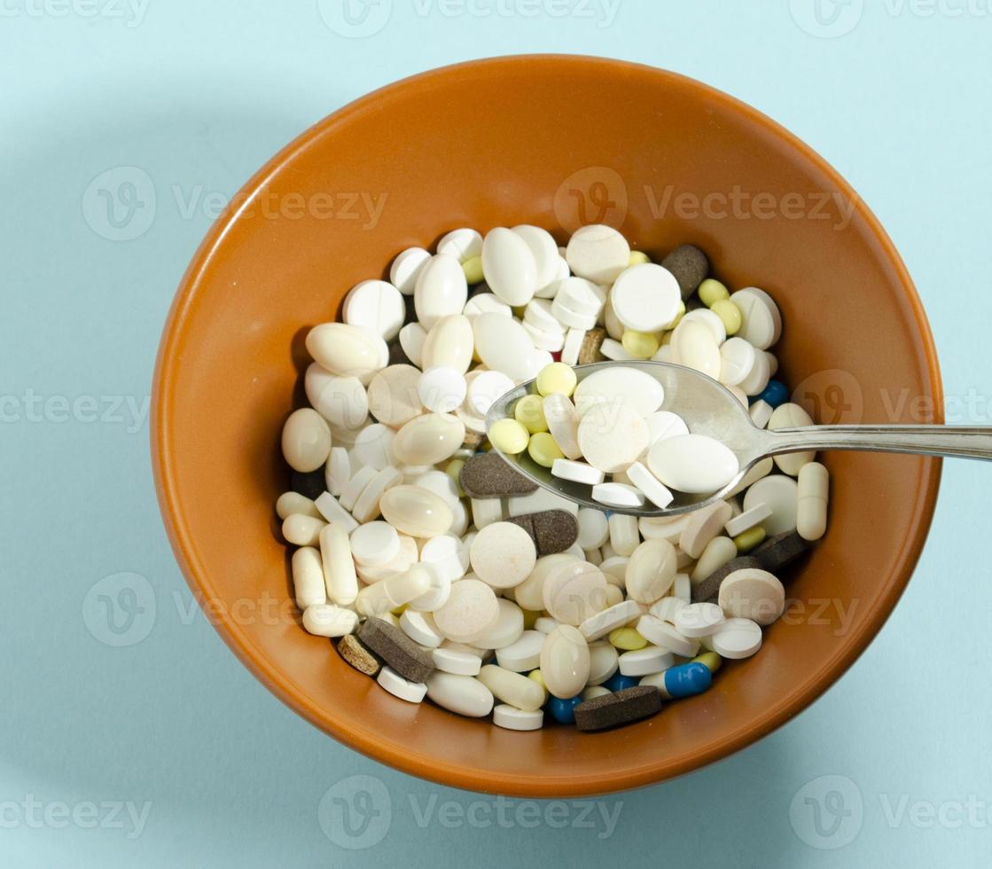 Medication with a spoon. Plate with medicines on a blue background. photo