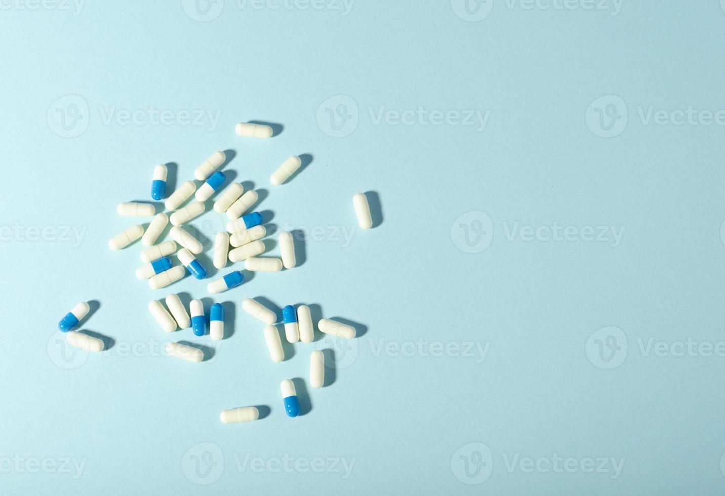 Randomly scattered pills. White and blue pills on blue background. Place for text. photo