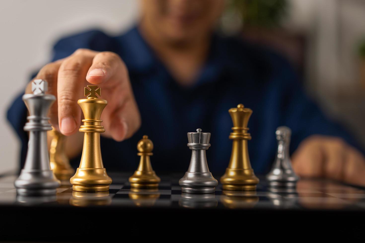 Close up of hands of a business man moving king golden chess to defeat opponent the chess game is development analysis, strategy, and plan, the management or leadership concept. photo