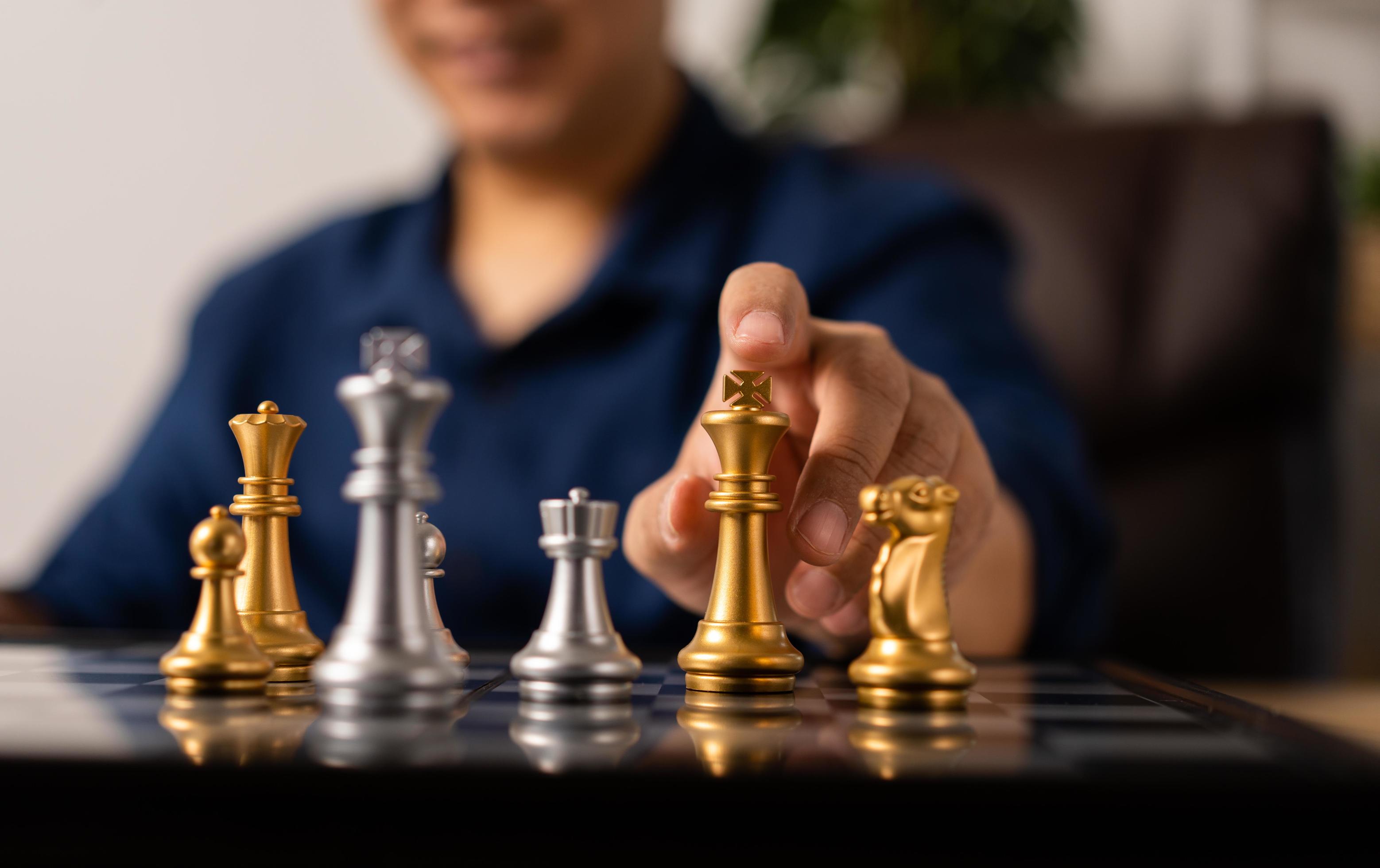 Close up of hands of a business man moving king golden chess to defeat  opponent the chess game is development analysis, strategy, and plan, the  management or leadership concept. 22804709 Stock Photo