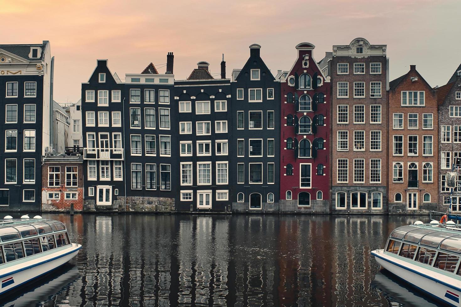 Beautiful cityscape scenery with boats in canal and intersting architecture drunken houses at Amsterdam City, Netherlands photo