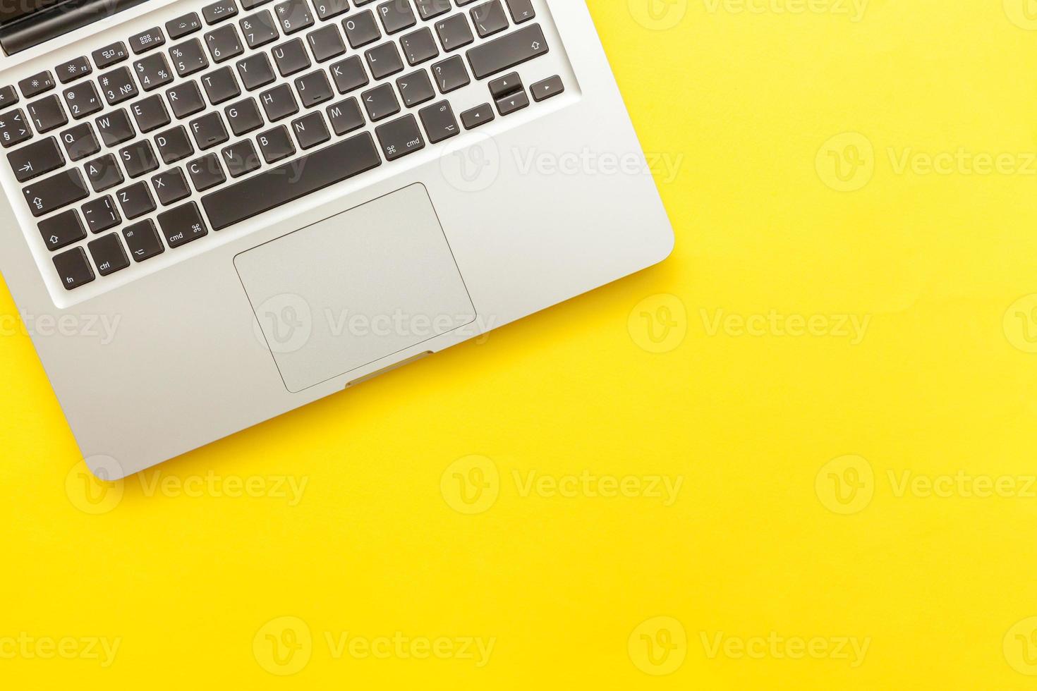 Keyboard laptop computer isolated on yellow desk background. Modern Information technology and sofware advances photo