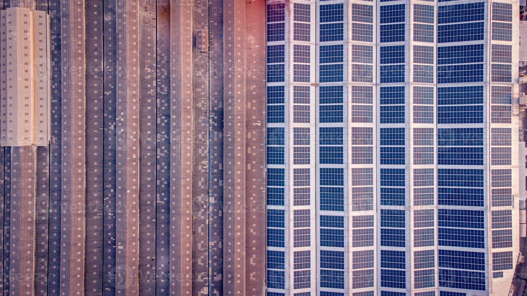 A large solar cell roof on an industrial building Generating electricity for the plant during daytime according to policies and measures to reduce global warming by taking high-angle shots from drones photo