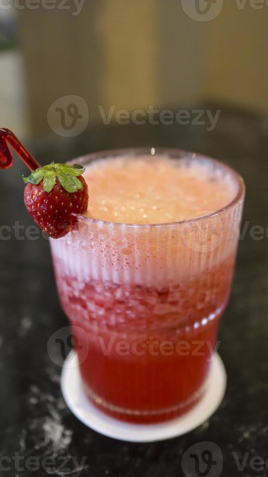 A glass of strawberry juice at the table with a fancy straw. photo