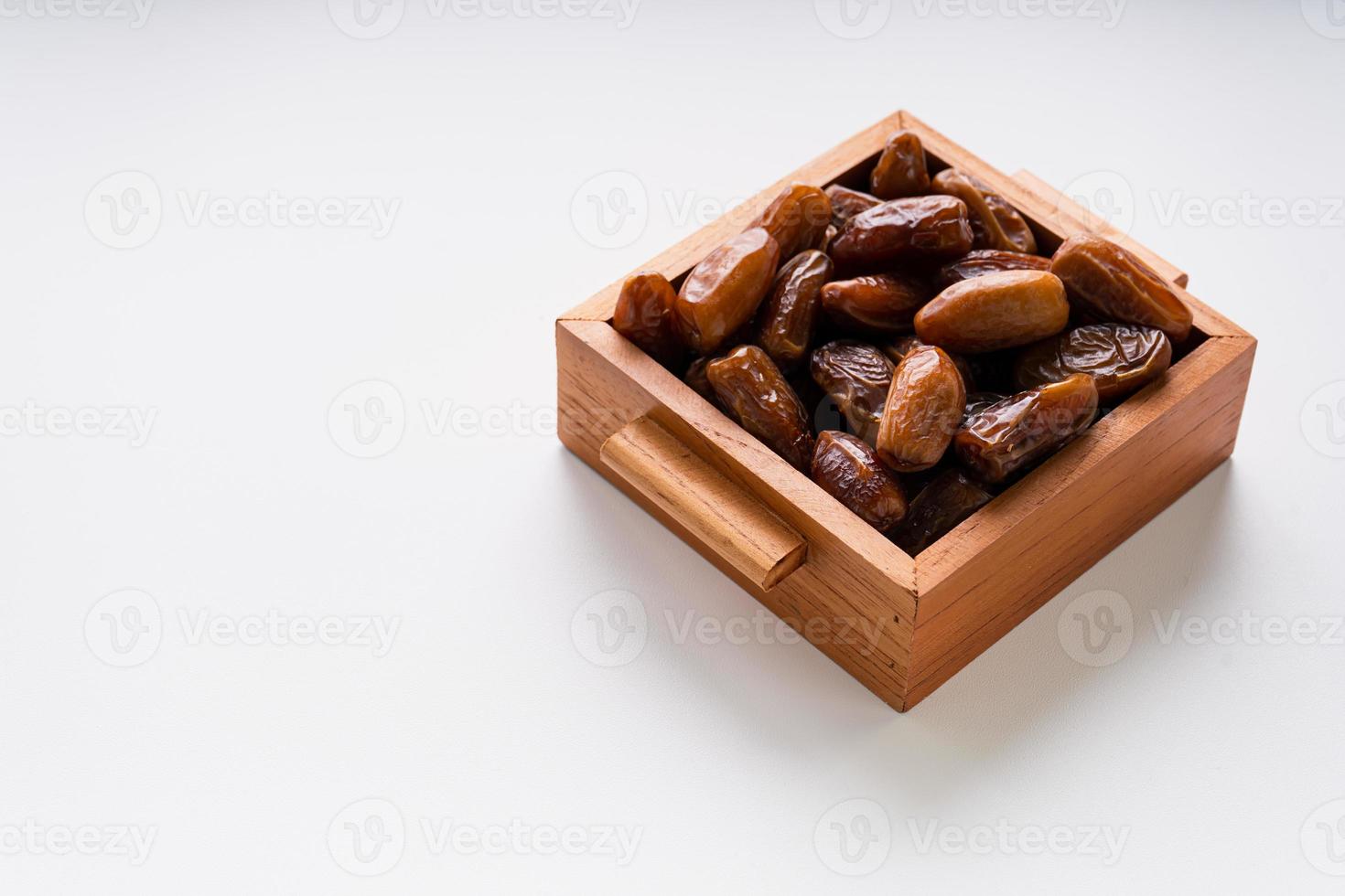 Dried dates fruit in wooden tray with soft napkin isolated on white background. photo