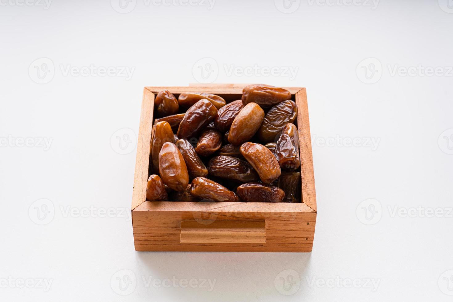 Dried dates fruit in wooden tray with soft napkin isolated on white background. photo