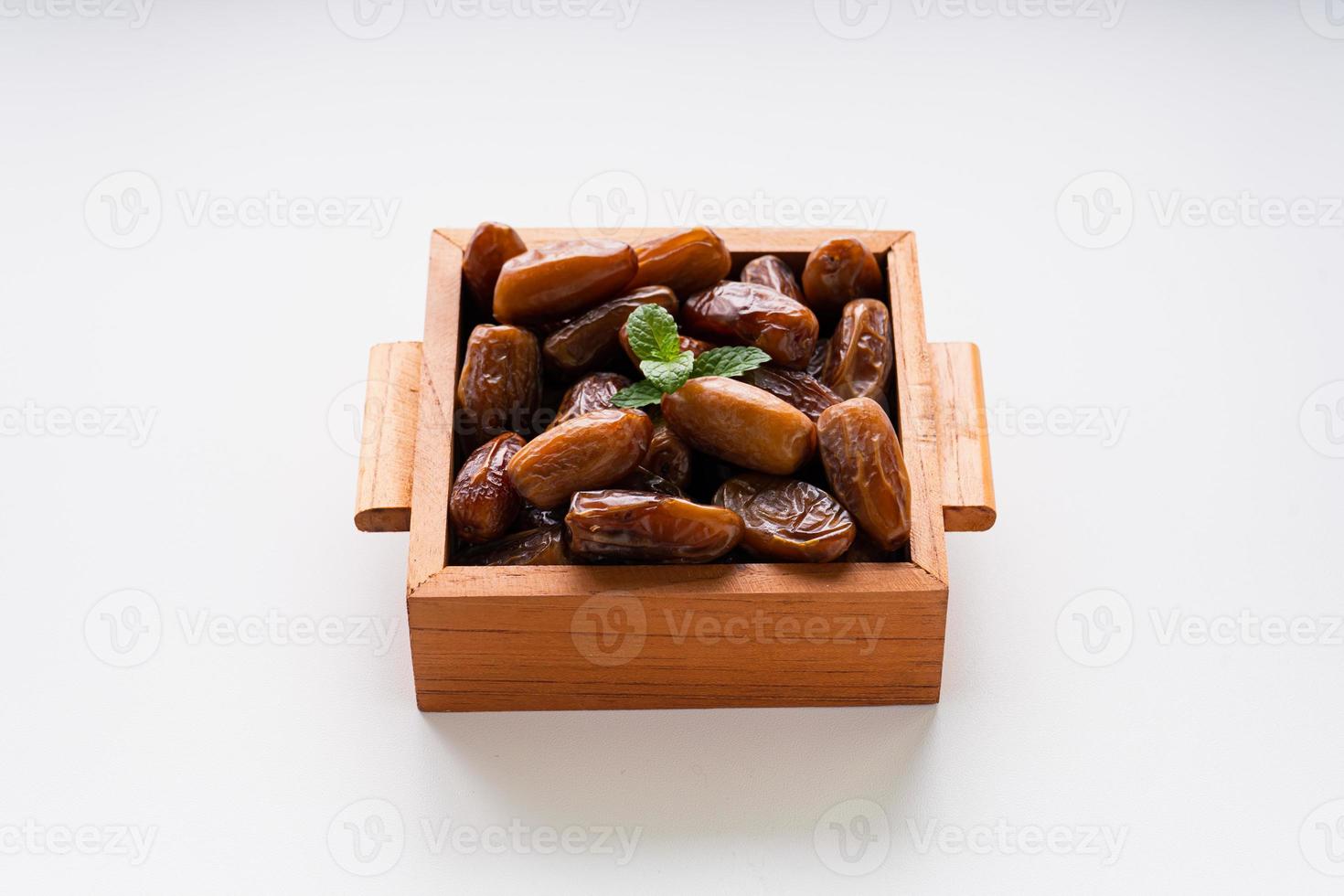 Dried dates fruit in wooden tray with soft napkin isolated on white background. photo