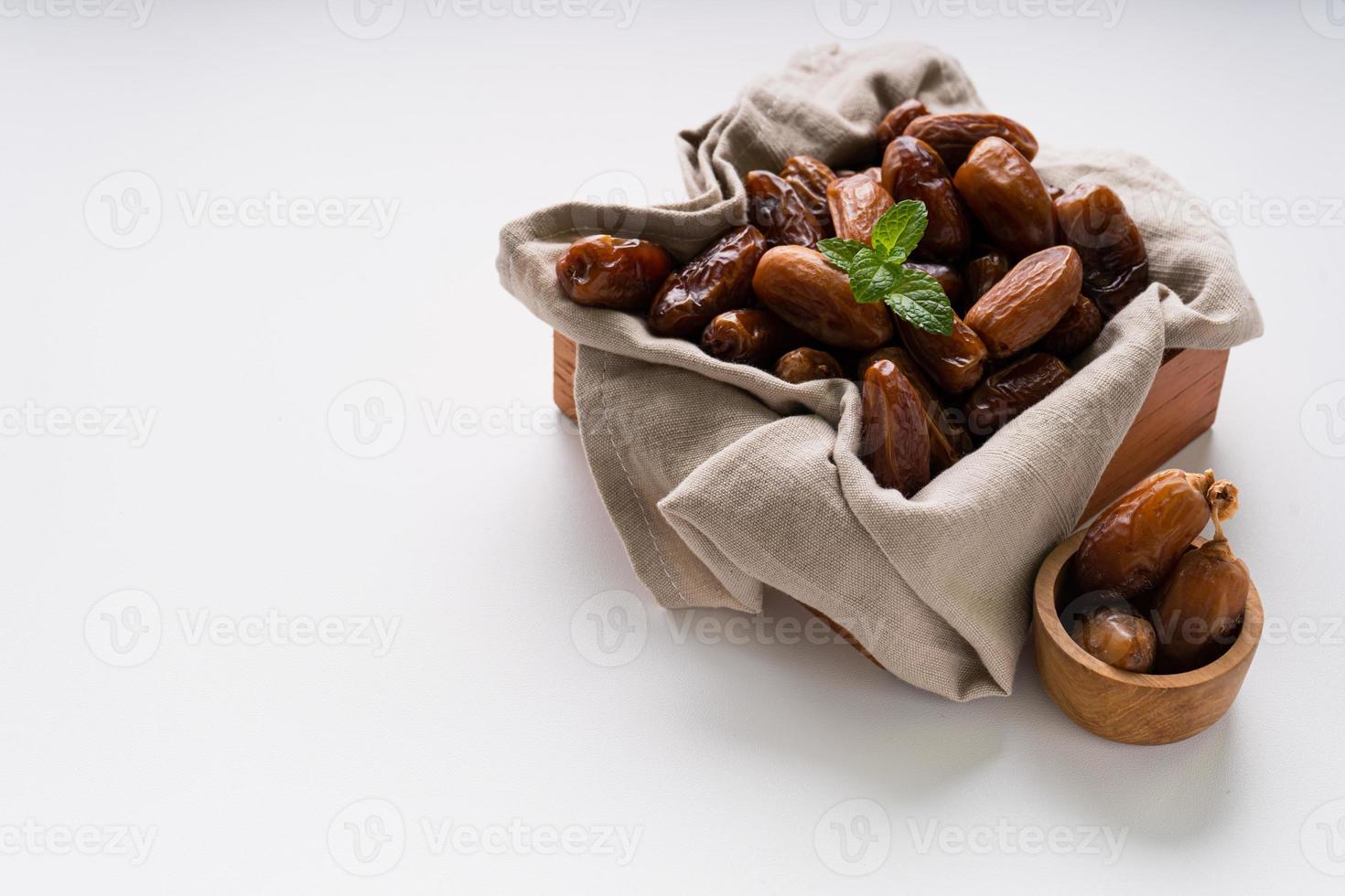 Dried dates fruit in wooden tray with soft napkin isolated on white background. photo