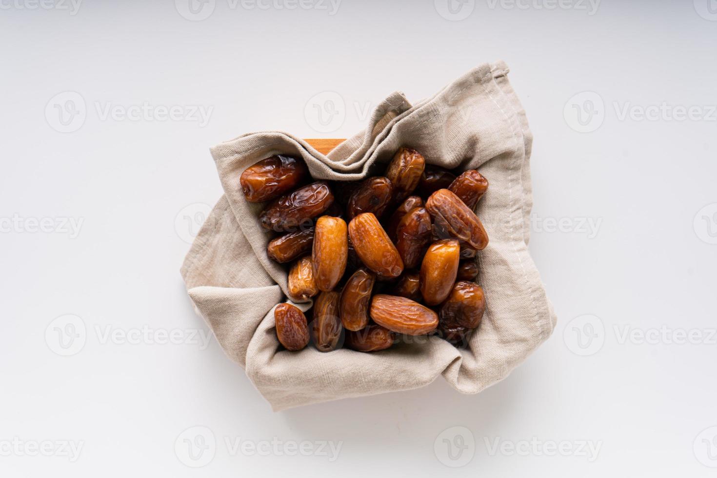 Dried dates fruit in wooden tray with soft napkin isolated on white background. photo