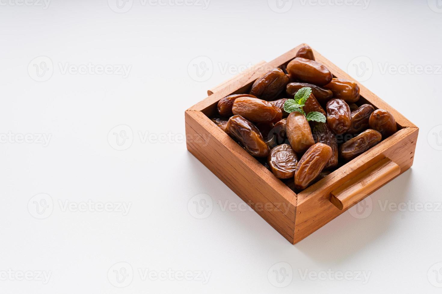 Dried dates fruit in wooden tray with soft napkin isolated on white background. photo