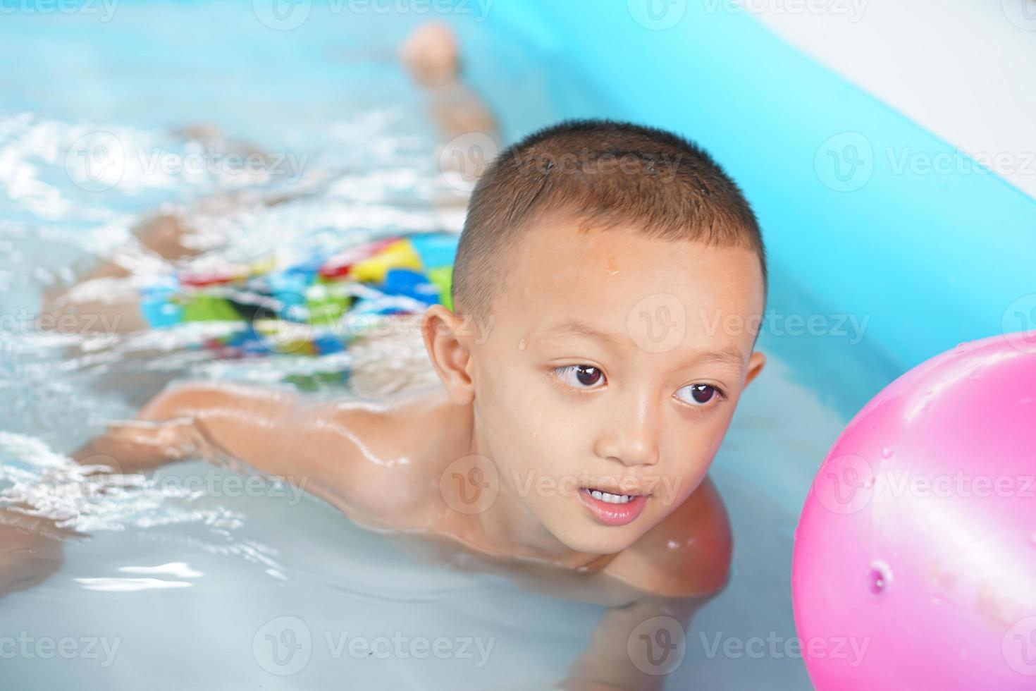 Hot weather. Boy playing with water happily in the tub. photo