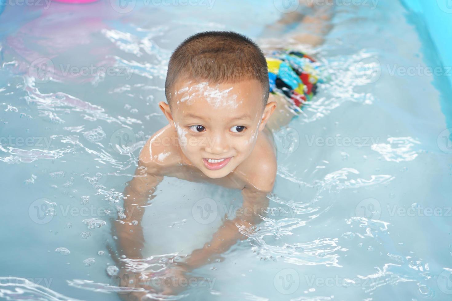 Hot weather. Boy playing with water happily in the tub. photo