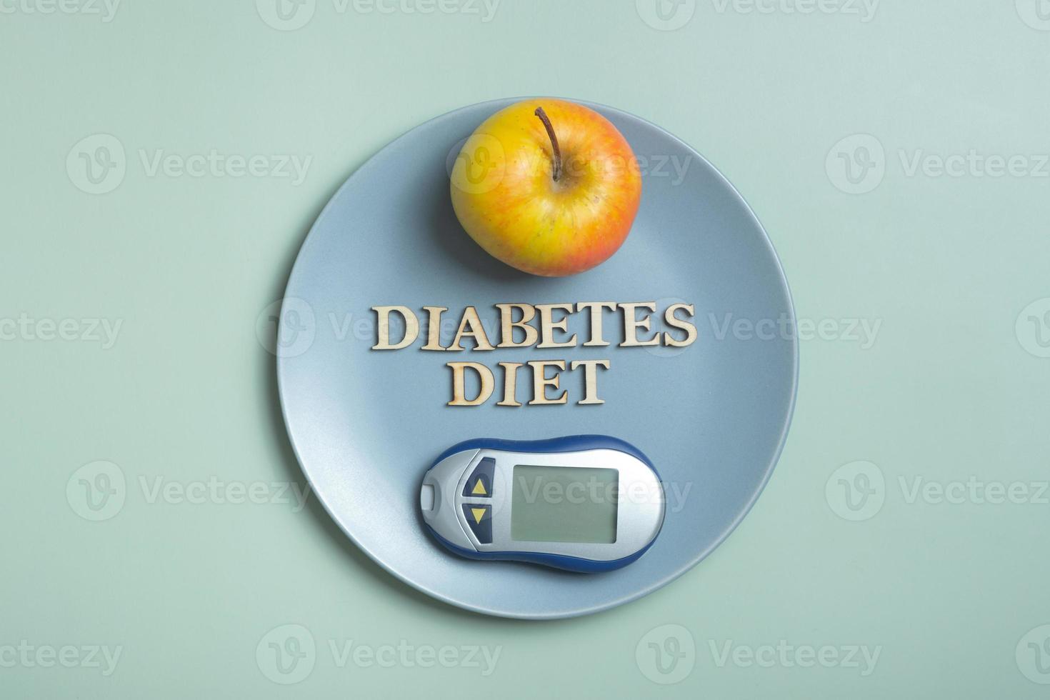 Diabetes Diet Plan text. Glucometer and plate with apple on colored background flat lay, top view photo