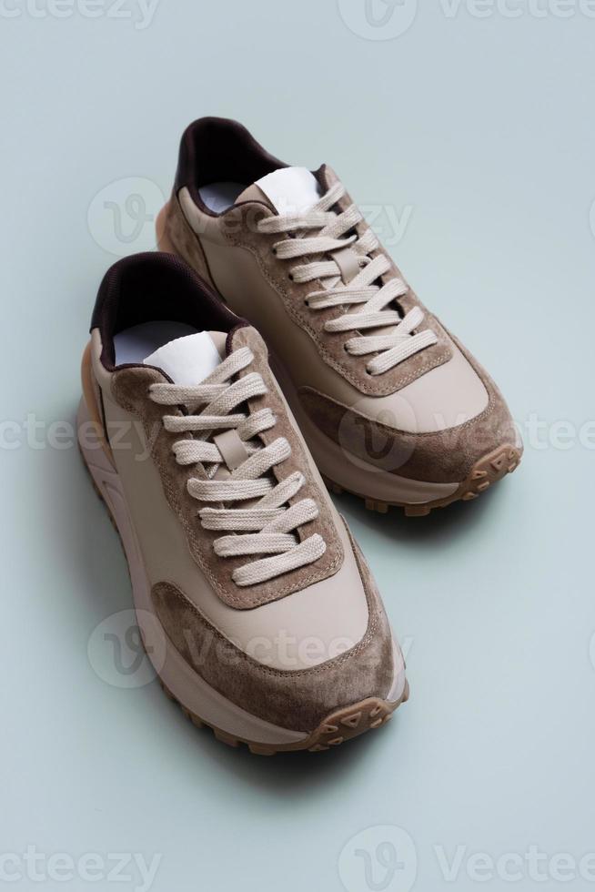 Beige women's leather sneakers on a green-beige background. Spring or autumn casual shoes photo