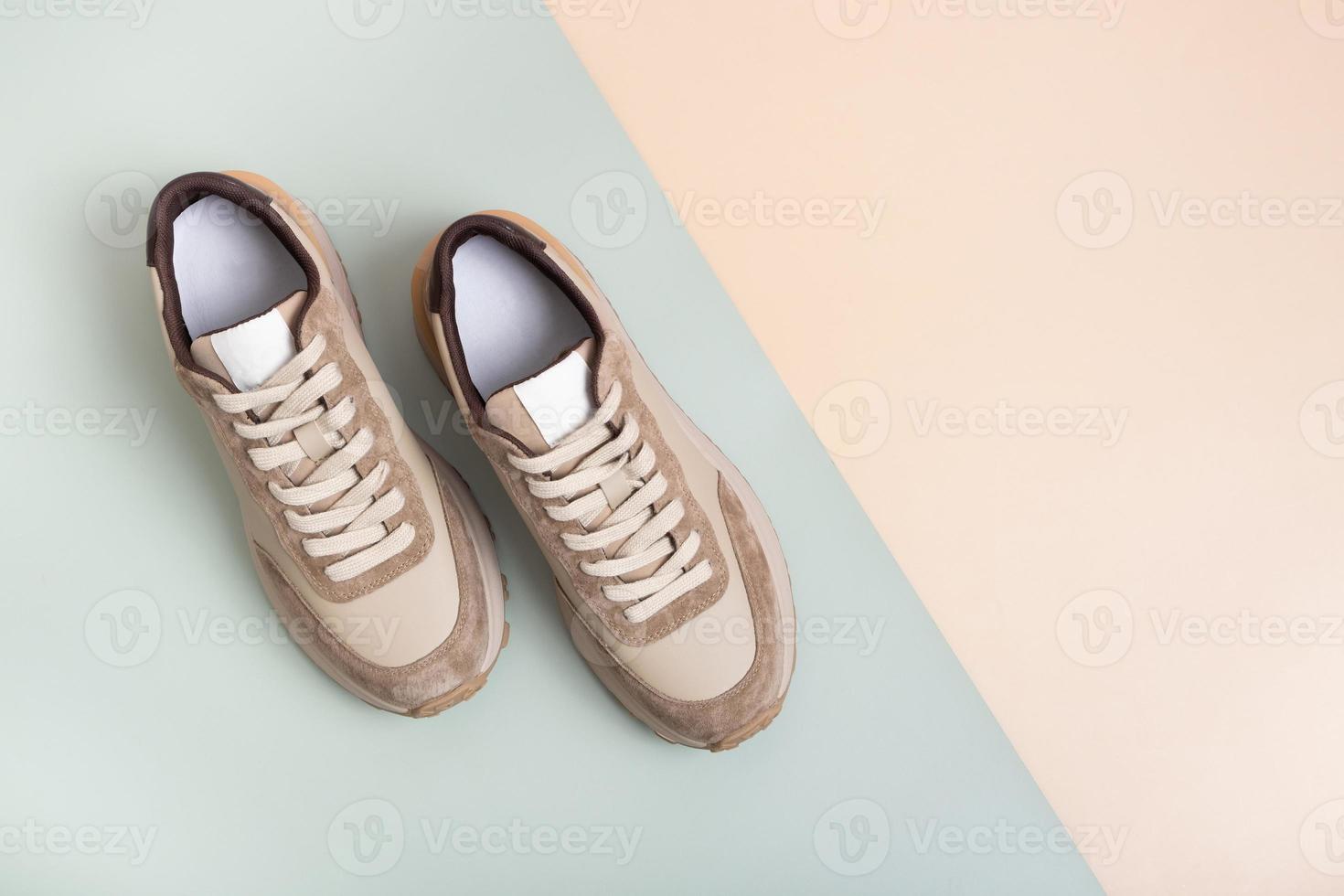 Beige women's leather sneakers top view on a green-beige background. Spring or autumn casual shoes photo