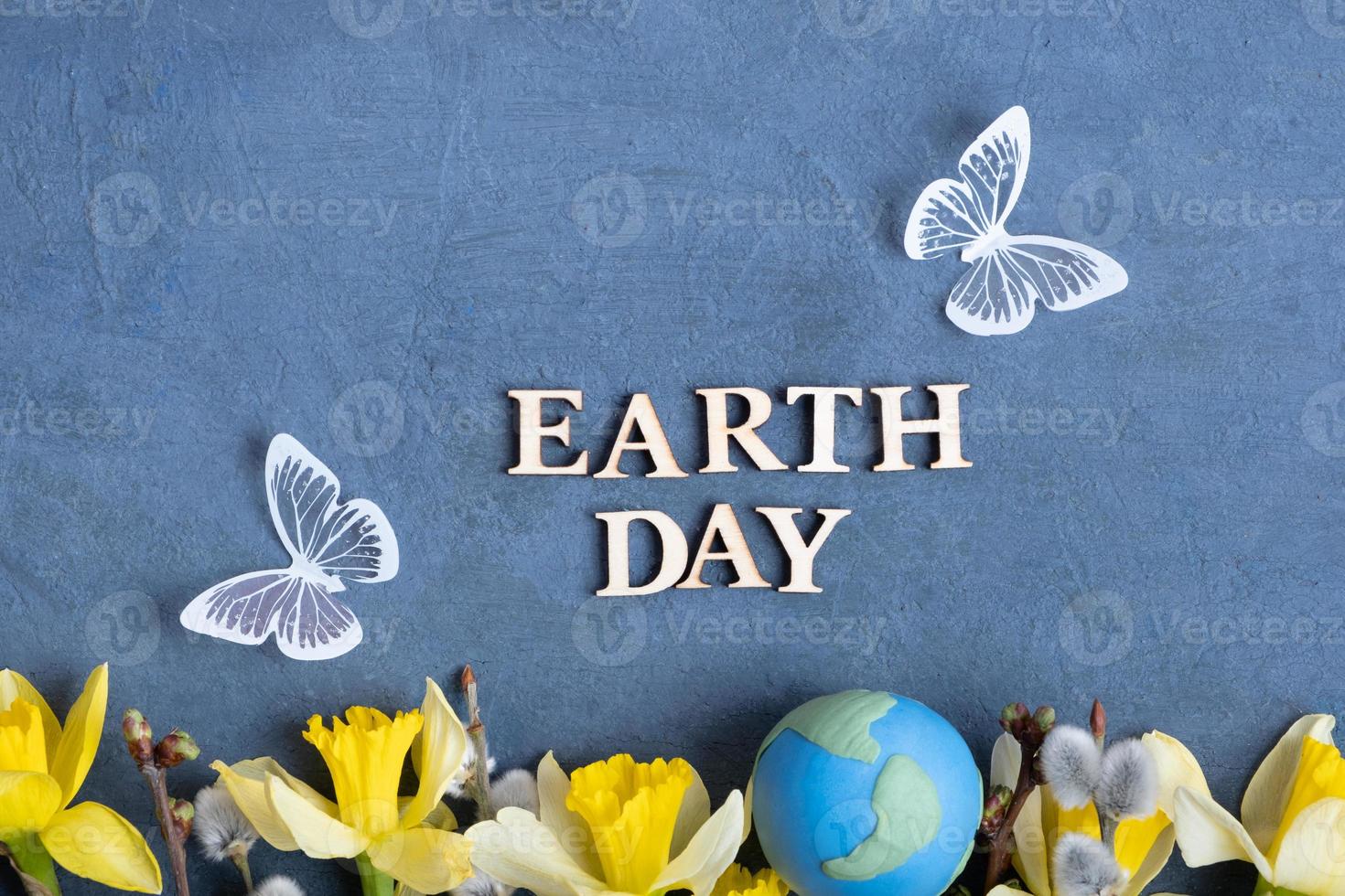 Earth day text with globe, flowers and butterfly. Happy Earth day concept flat lay, top view photo