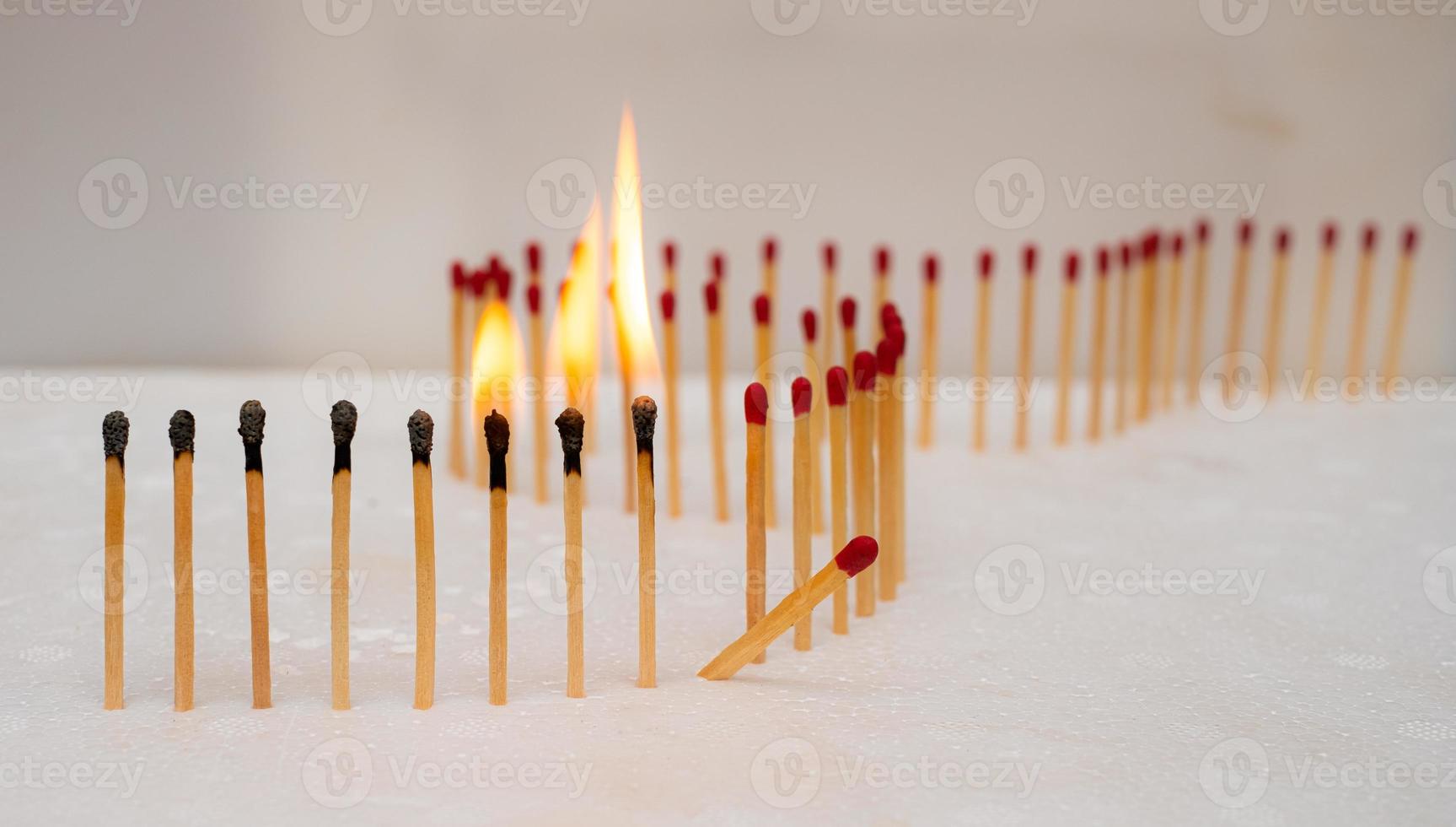 Row of burning matches and all matches on white background. spread of fire one match isolated to stop fire concept of the power of difference photo