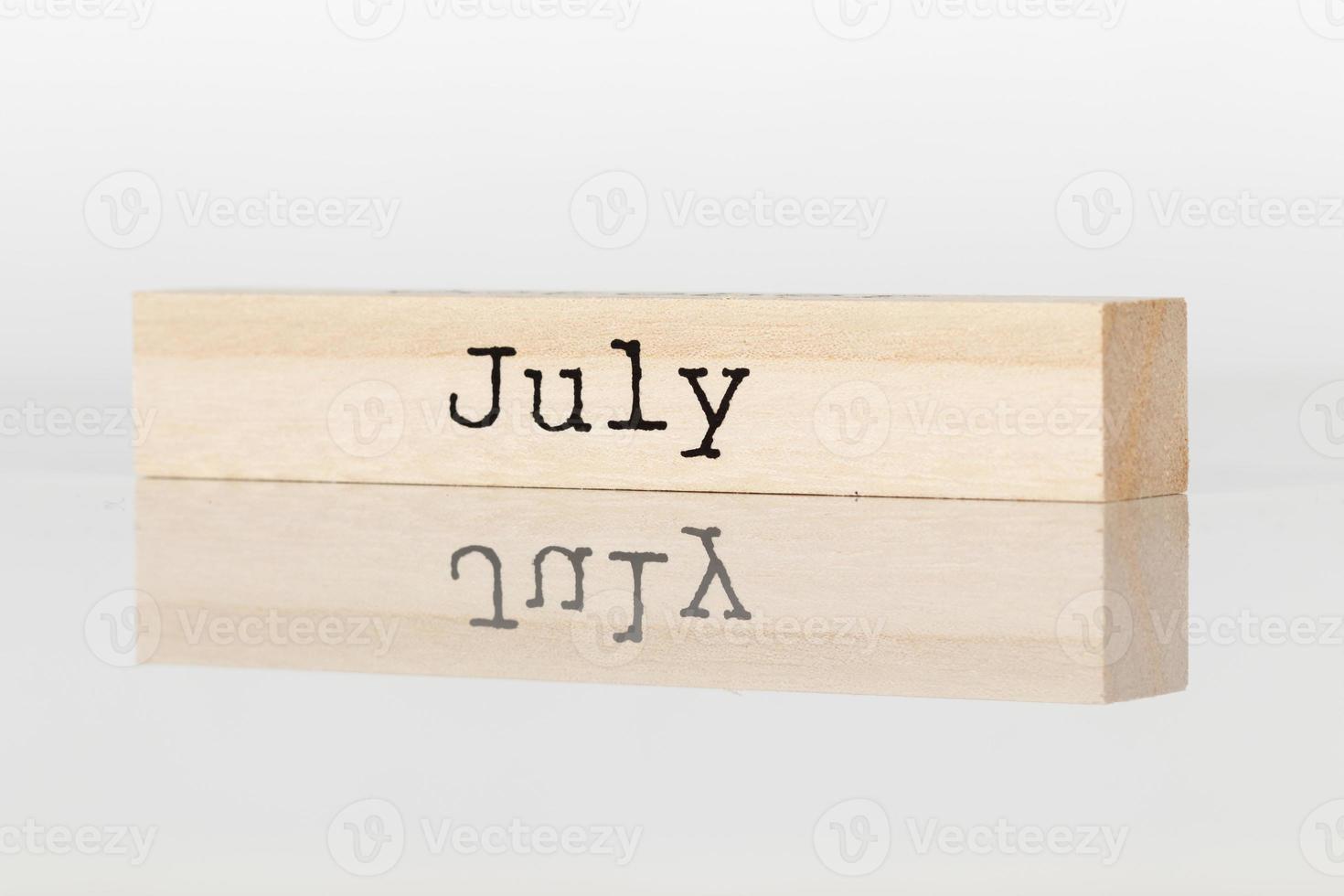 wooden cube with the inscription July on a white background photo