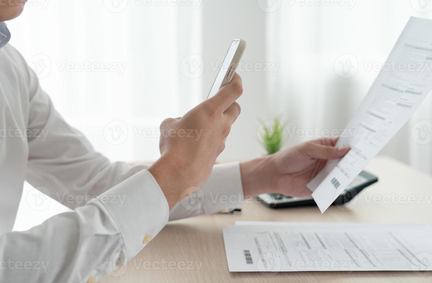 business man use phone to scan barcode or QR codes to pay credit card bill after receiving document invoice online. payment, receive, paying electricity, digital payments without money, technology photo