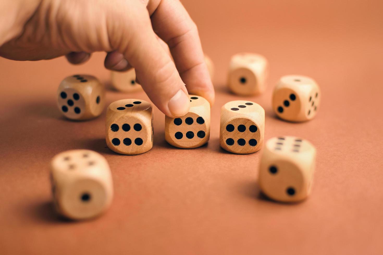 Closeup shot of hand holding wooden dice with dot like numbers on brown background photo