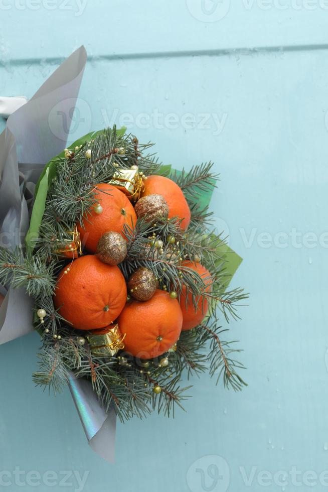 Christmas bouquet of fir branches, mandarins and little gift boxes on blue background. New Year. selective focus. photo