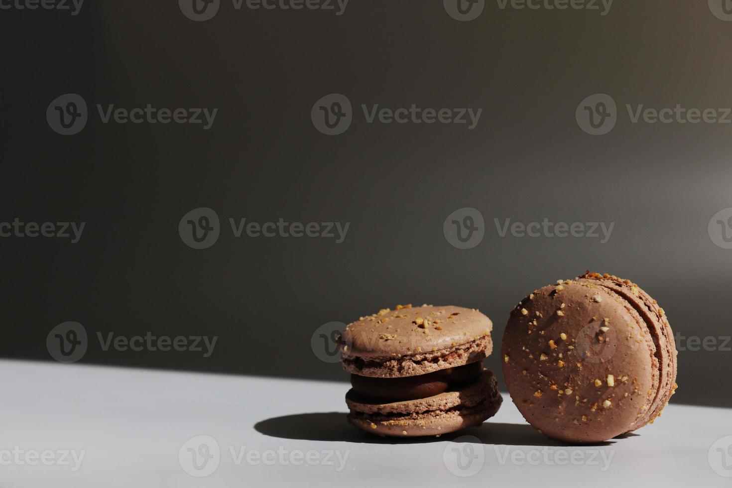 Sweet brown chocolate french macaroons or macarons dessert isolated on white background with light rays from window. copy space. photo