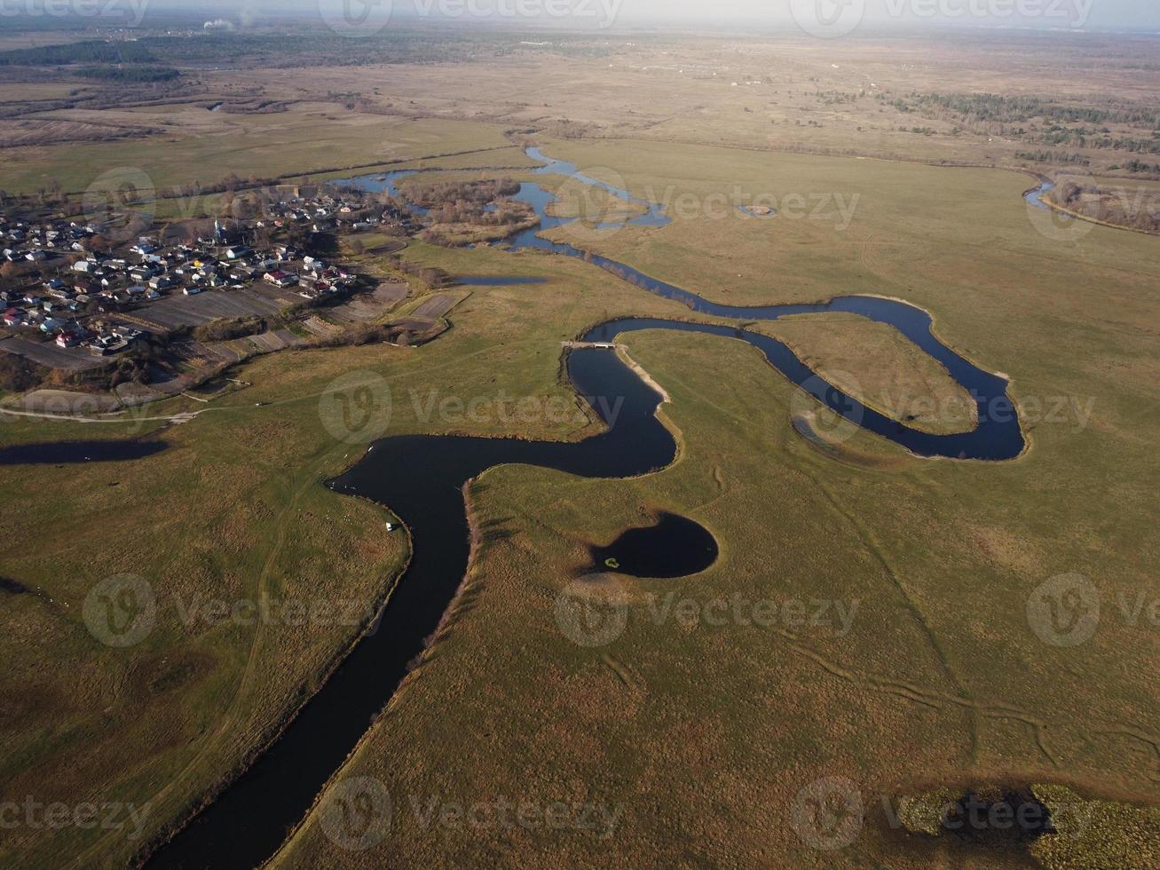 aerial view of a beautiful winding river flows among the fields, which flows picturesquely, creating incredible landscapes. between flooded fields and swamps. photo