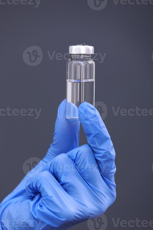 Development and creation of a coronavirus vaccine COVID-19 .Coronavirus Vaccine in glass bottle in hand of doctor on gray background. Vaccine Concept of fight against coronavirus. photo