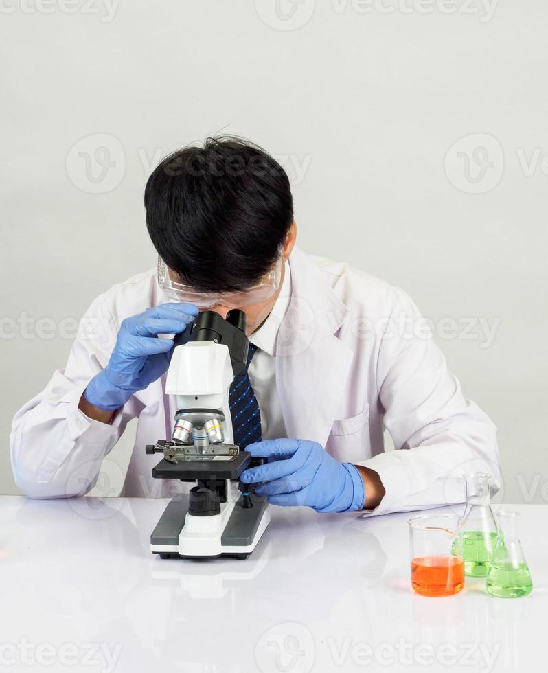 Asian man student scientist in reagent mixing laboratory In a science research laboratory with test tubes of various sizes. on the floor in  laboratory chemistry lab white background. photo