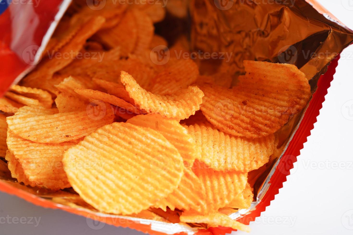 papas fritas en bolsa abierta, delicioso condimento de barbacoa picante para crips, refrigerio frito en rodajas finas comida rápida. foto