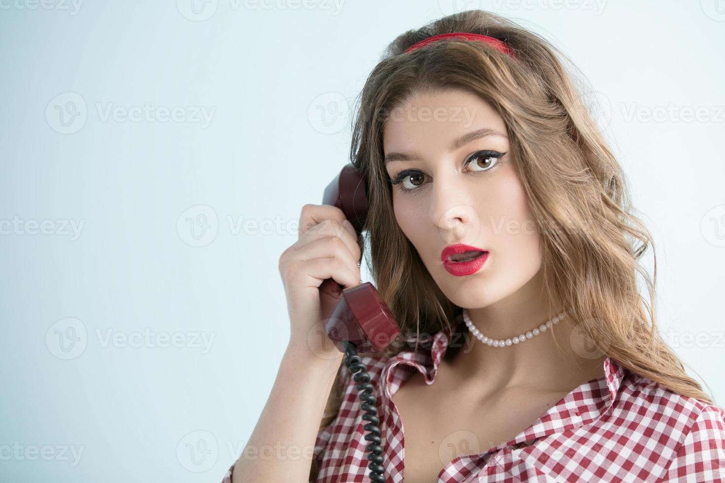 Woman in the style of the fifties. Beautiful retro woman holding a telephone receiver. photo