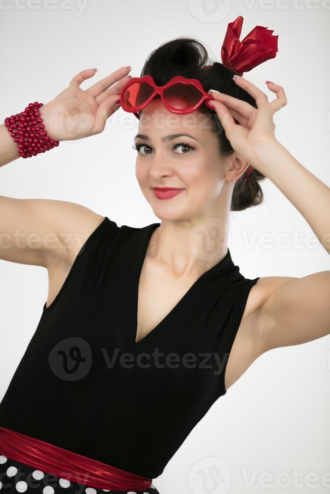 Beautiful retro girl takes off red glasses photo