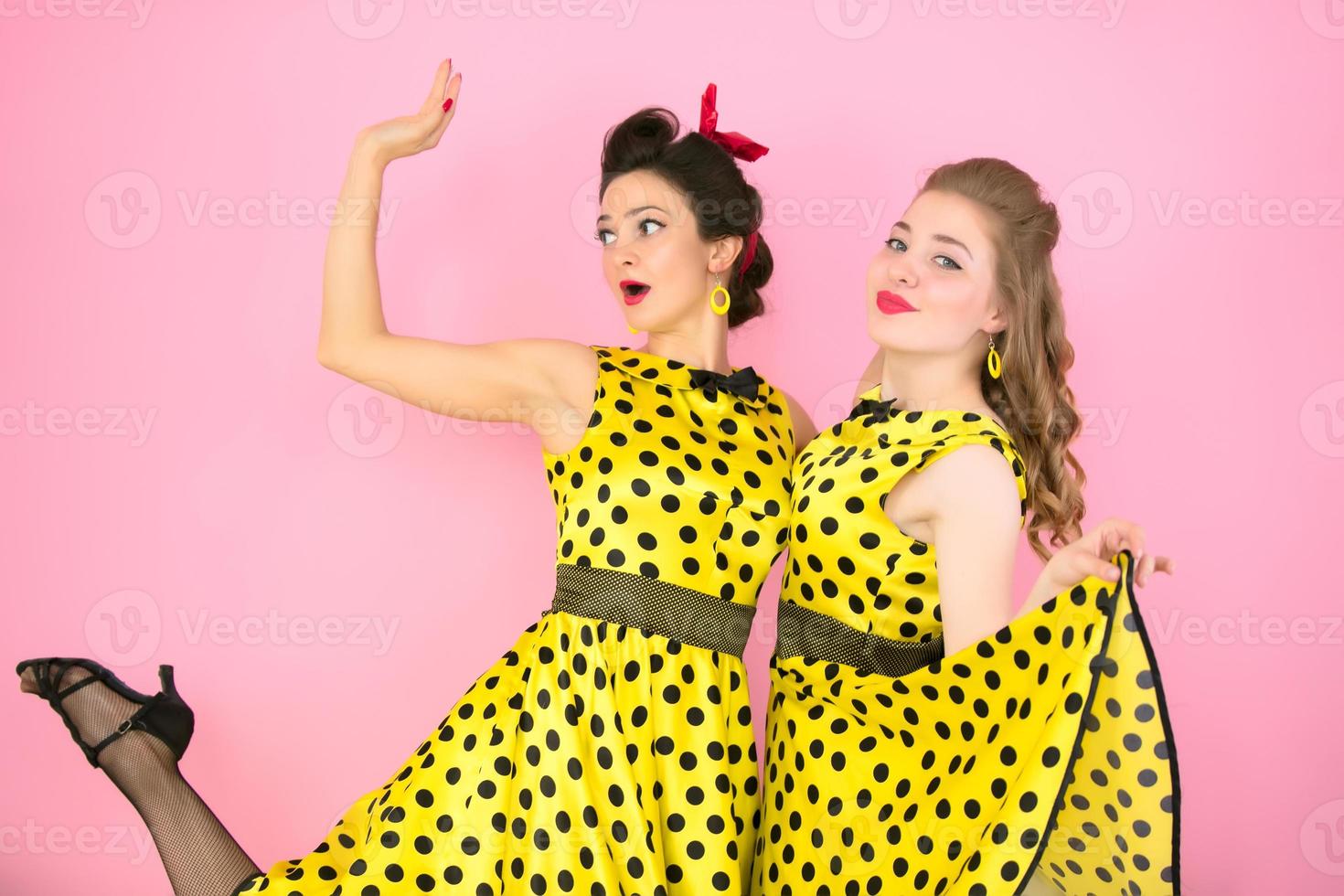 retro chicas. dos mujer en amarillo vestidos en un rosado antecedentes. foto