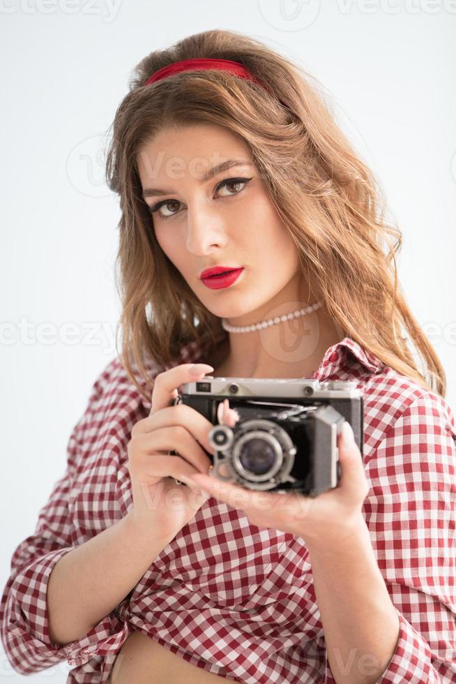 hermosa niña con retro cámara. mujer fotógrafo en el estilo de el cincuenta foto