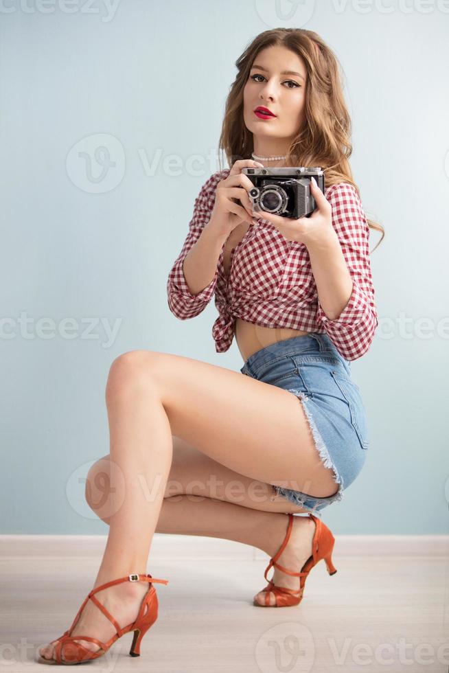 Retro girl in heels with a retro camera. photo