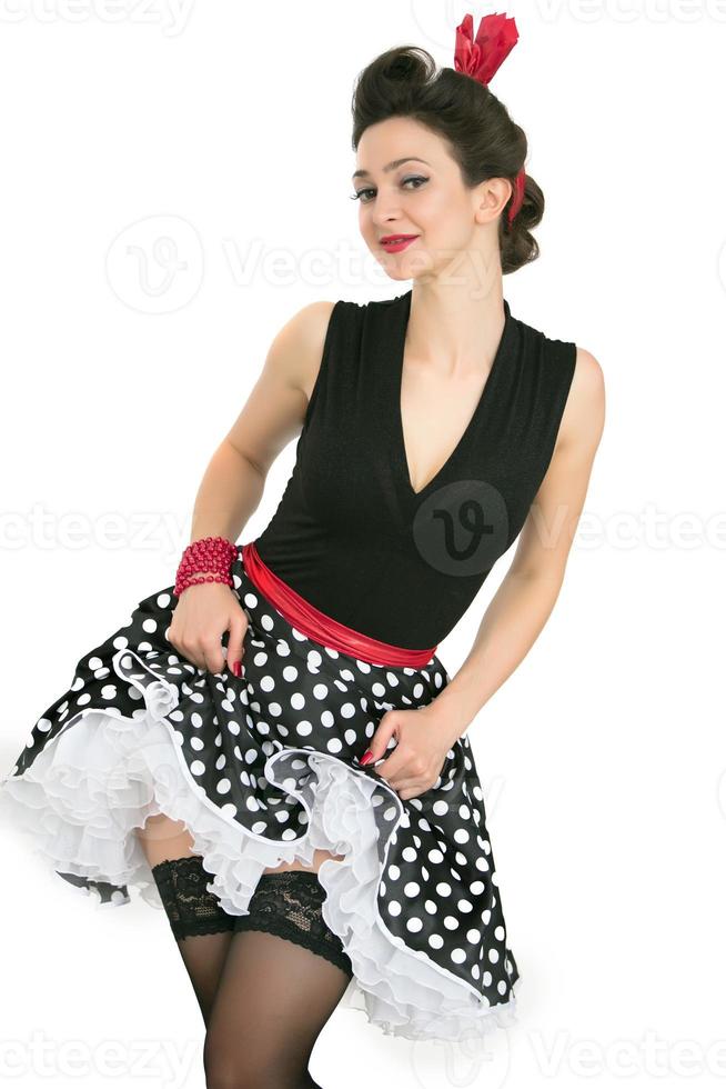 A retro girl is pinuped in black stockings and a polka dot skirt. Beautiful brunette in the style of the fifties. photo