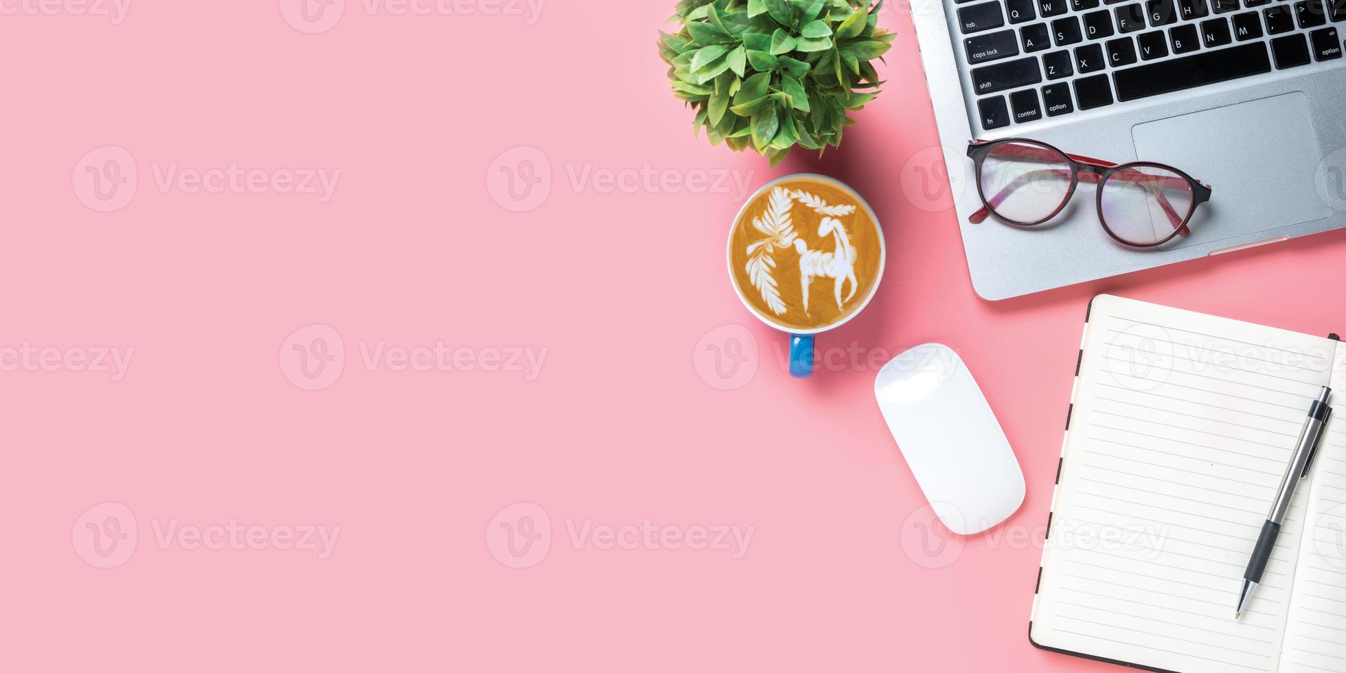 Office desk with computer, Pen, eyeglass, mouse, notebook, Cup of coffee on pink background, Top view with copy space, Mock up. photo