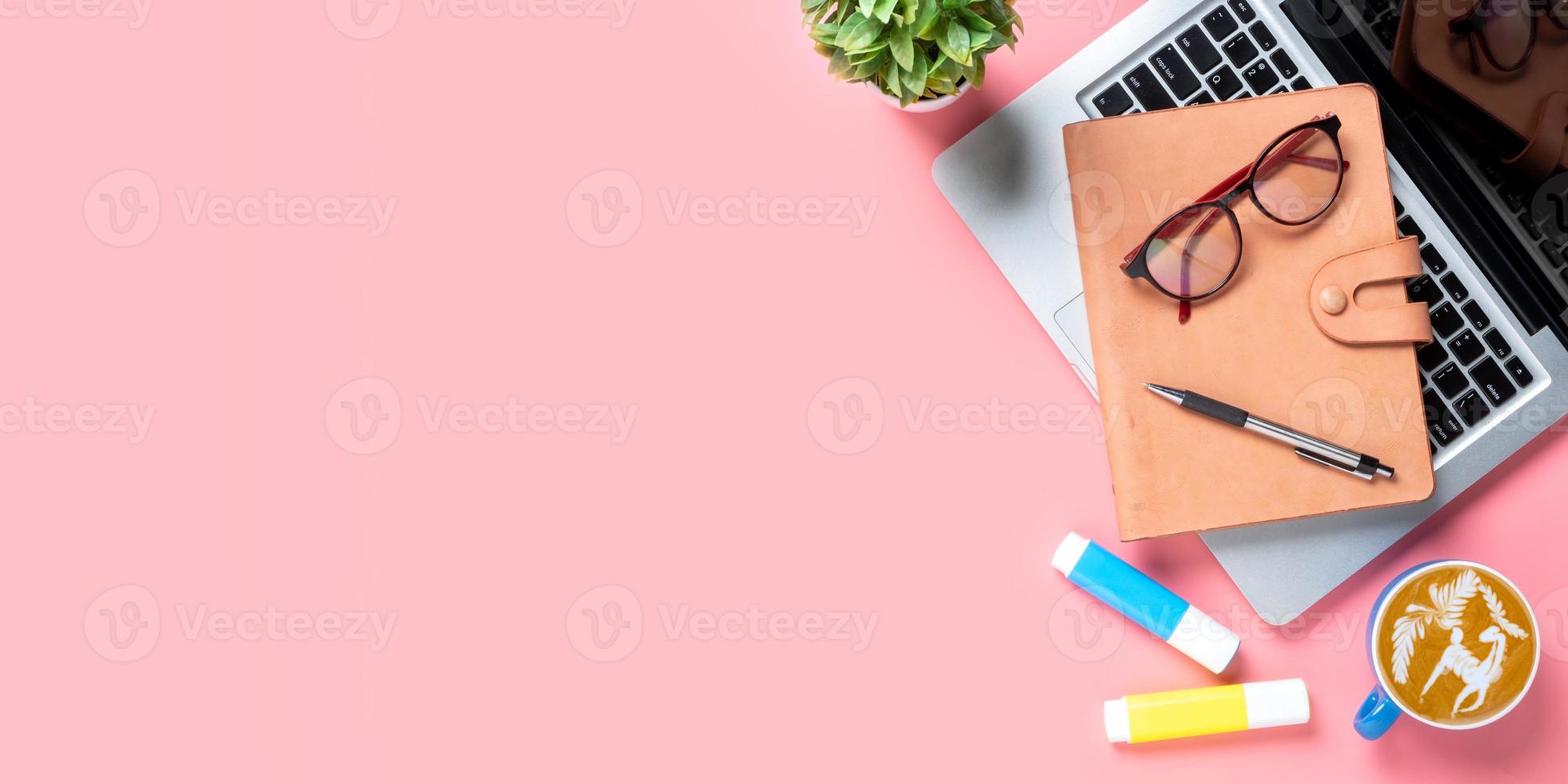 Office desk with computer, Pen, eyeglass, notebook, Cup of coffee on pink background, Top view with copy space, Mock up. photo