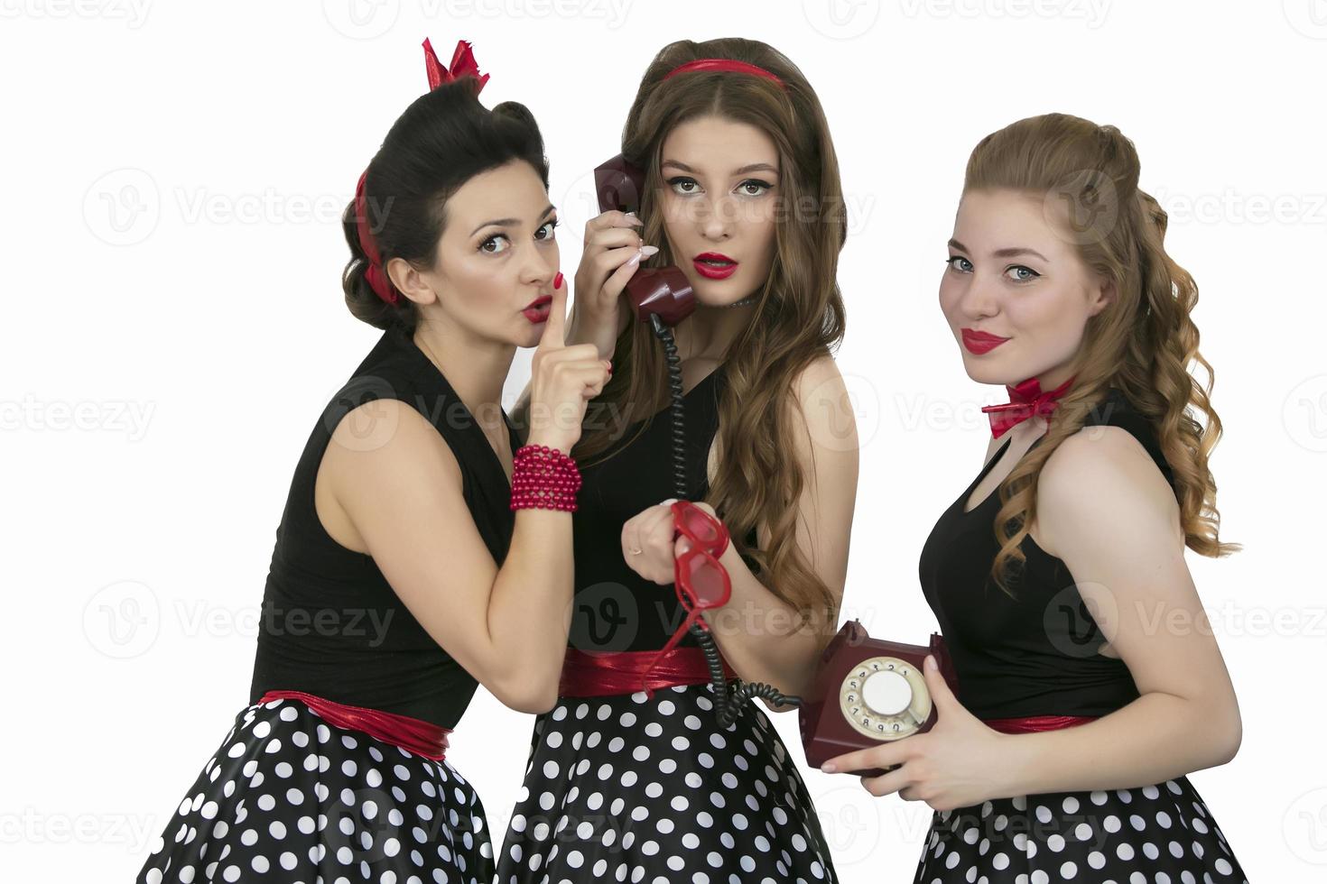 Three beautiful retro girls. Group of women with retro telephone. The girlfriends are discussing the telephone conversation. Gossips. photo