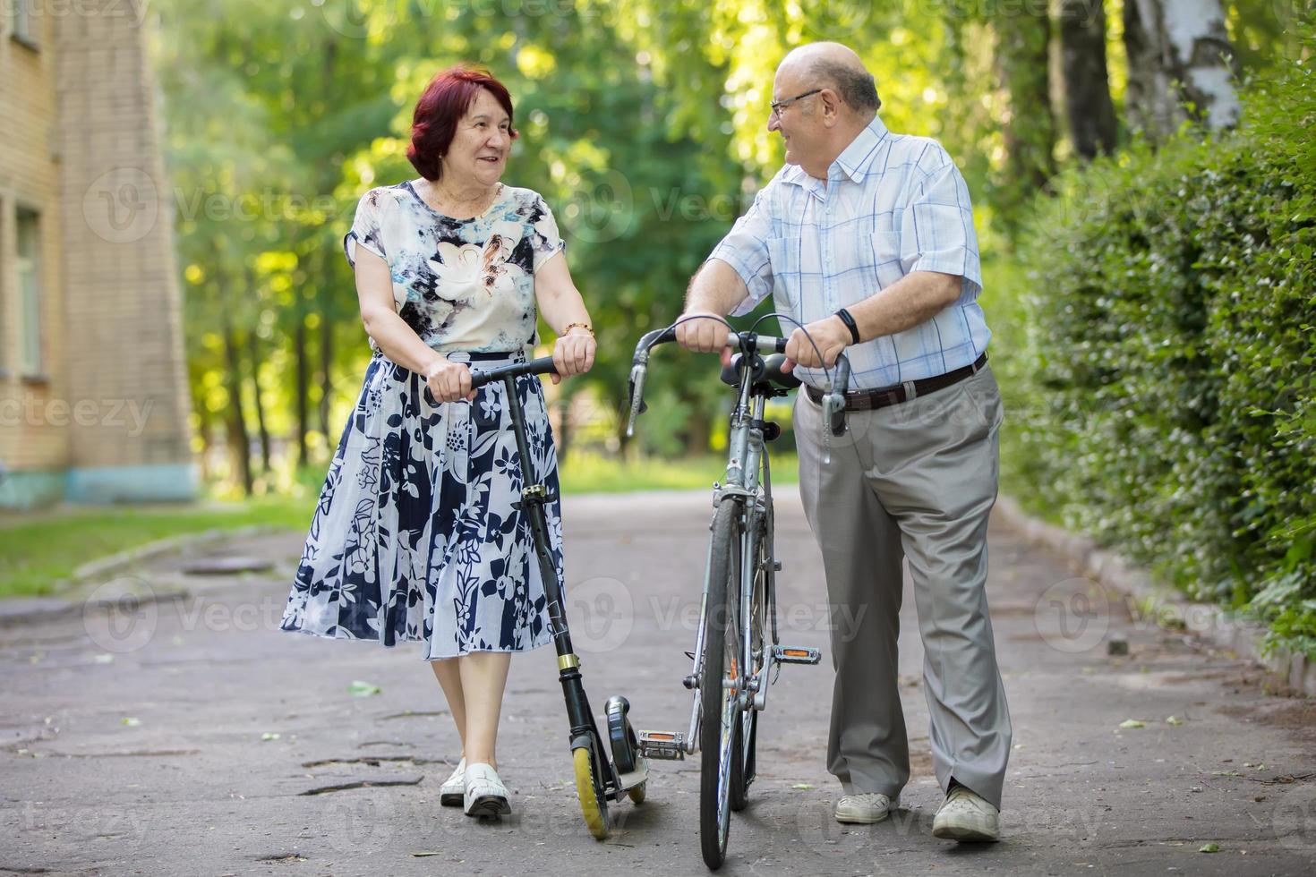 Happy elderly couple with a bicycle. Handsome man and woman senior citizens. Husband and wife of old age in the park. photo