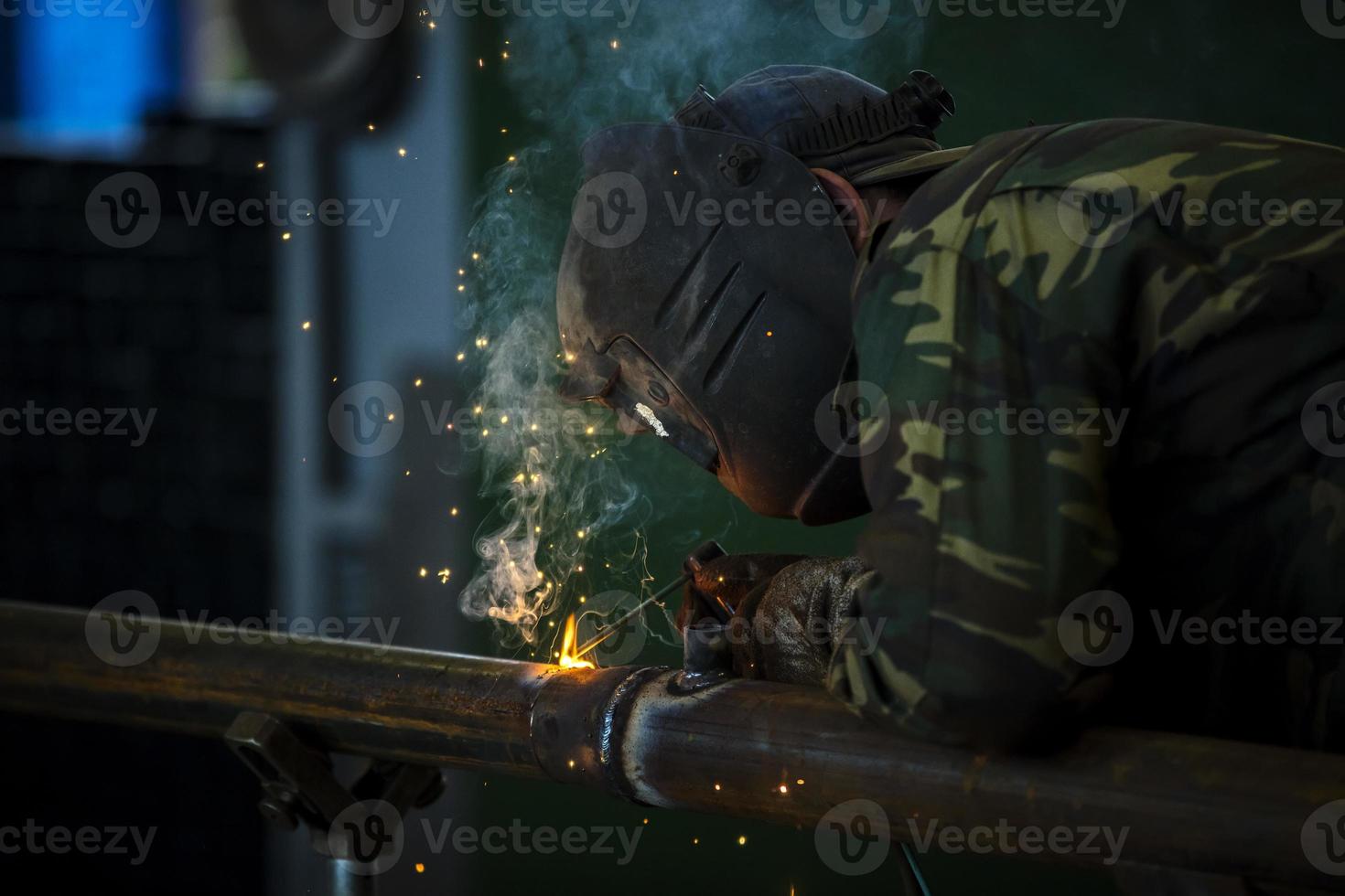 Welder at work. Man in a protective mask. The welder makes seams on the metal. Sparks and smoke when welding. photo