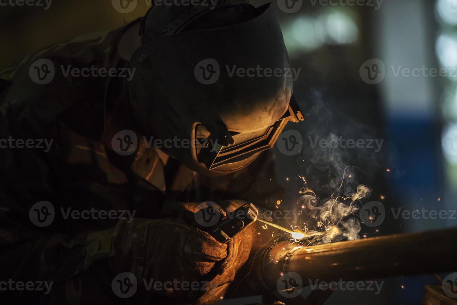 Welder at work. Man in a protective mask. The welder makes seams on the metal. Sparks and smoke when welding. photo